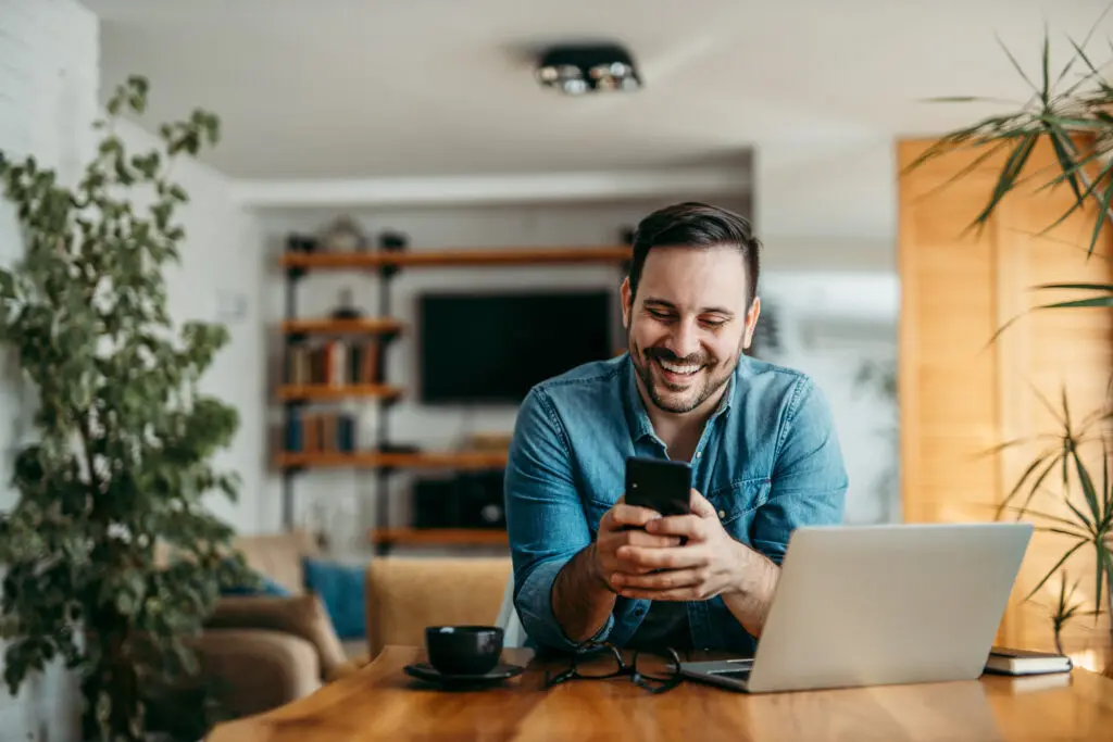 Xfinity Mobile customer in Indiana enjoys fast WiFi on their device on the Premium Unlimited plan. IMAGE: Portrait of a handsome man text messaging over smart phone, at home.