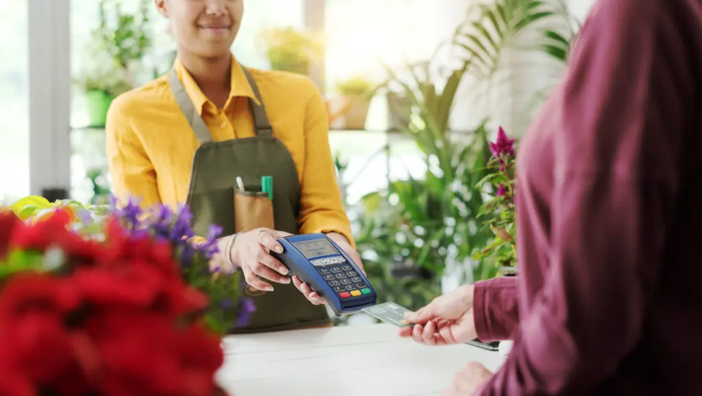 Small businesses in Indiana utilize Comcast Business to run their organization with fast, secure and reliable Internet and power their mobile devices. IMAGE: Customer at the flower shop, she is paying with a credit card, cashless payments concept