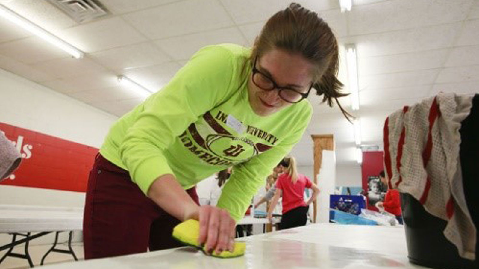 Young woman cleaning table with sponge