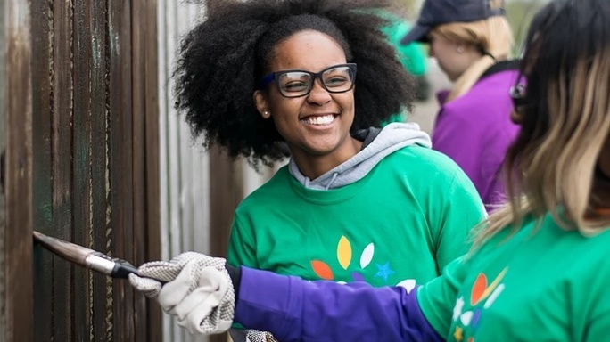 Comcast Cares Day volunteers paint a fence.