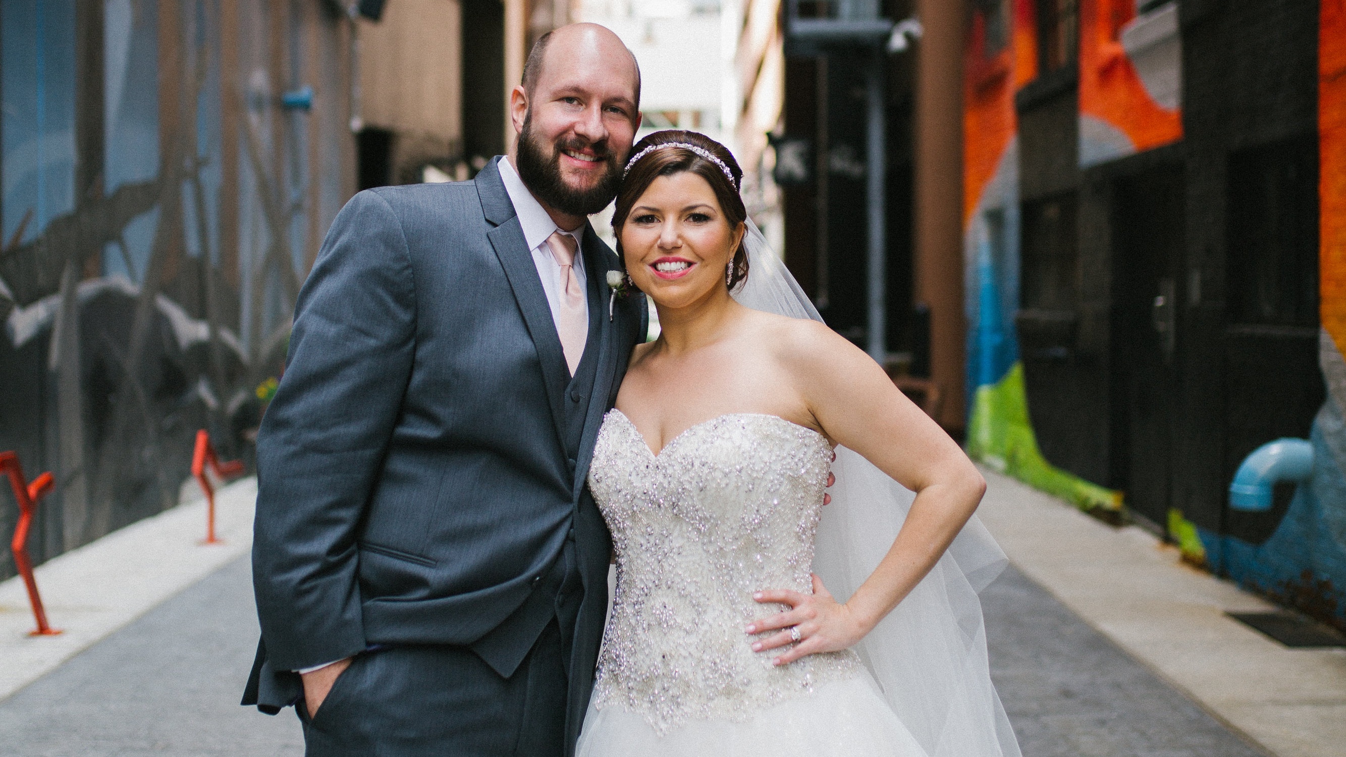 A bride and groom stand together in a street.