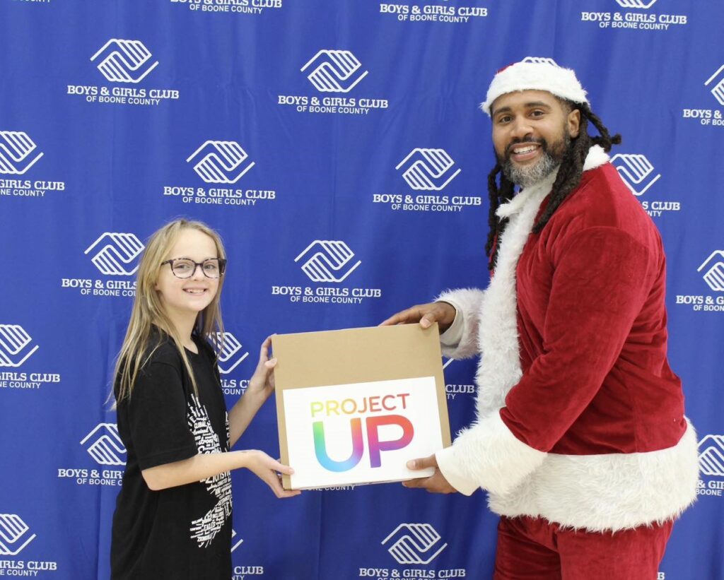Santa presents a laptop to a Boys & Girls Club member.