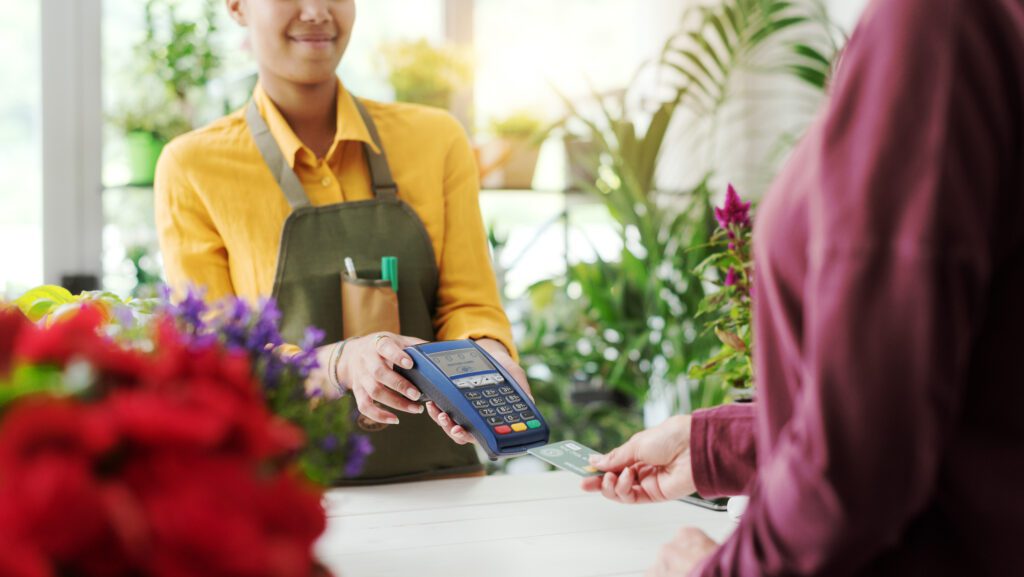 Small businesses in Indiana utilize Comcast Business to run their organization with fast, secure and reliable Internet and power their mobile devices. IMAGE: Customer at the flower shop, she is paying with a credit card, cashless payments concept